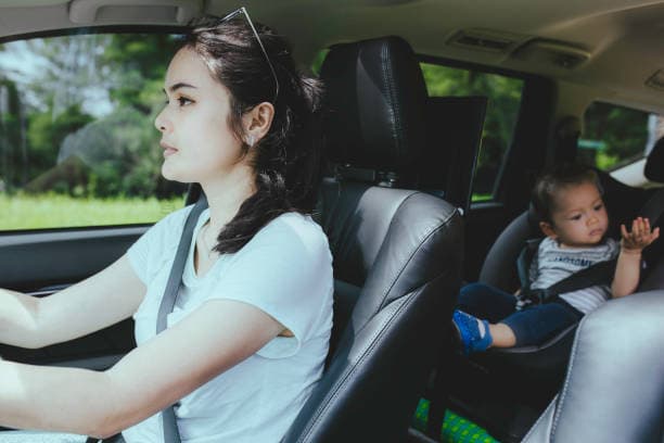 Driver at the wheel with a child in a car seat—typical daily driving